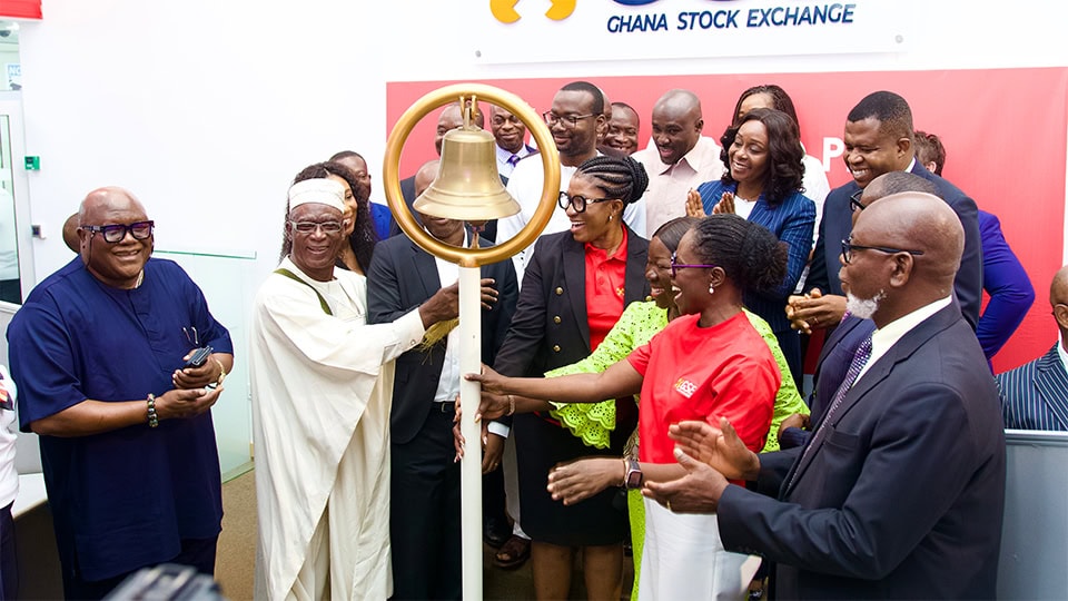 Crowd of people in formal and colourful clothing ringing a ceremonial bell, celebrate the successful IPO and share offer of Kasapreko PLC on the Ghana Stock Exchange.