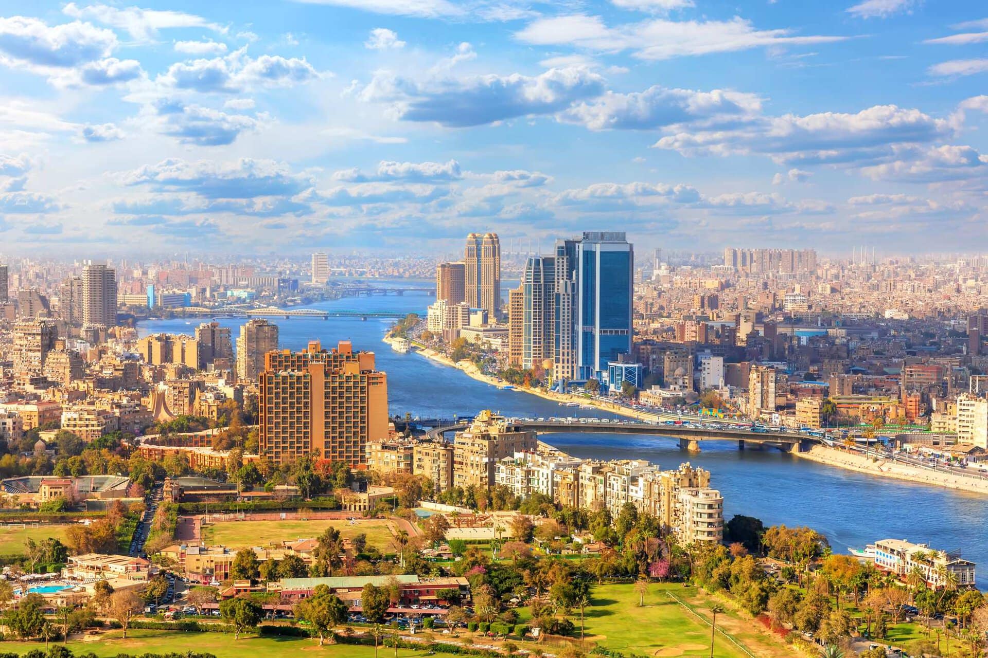 Aerial view of city of Cairo, Egypt, showing green park, river and tall buildings, blue sky, Illustrates share sale and IPO of Banque du Caire on the Egyptian Exchange EGX